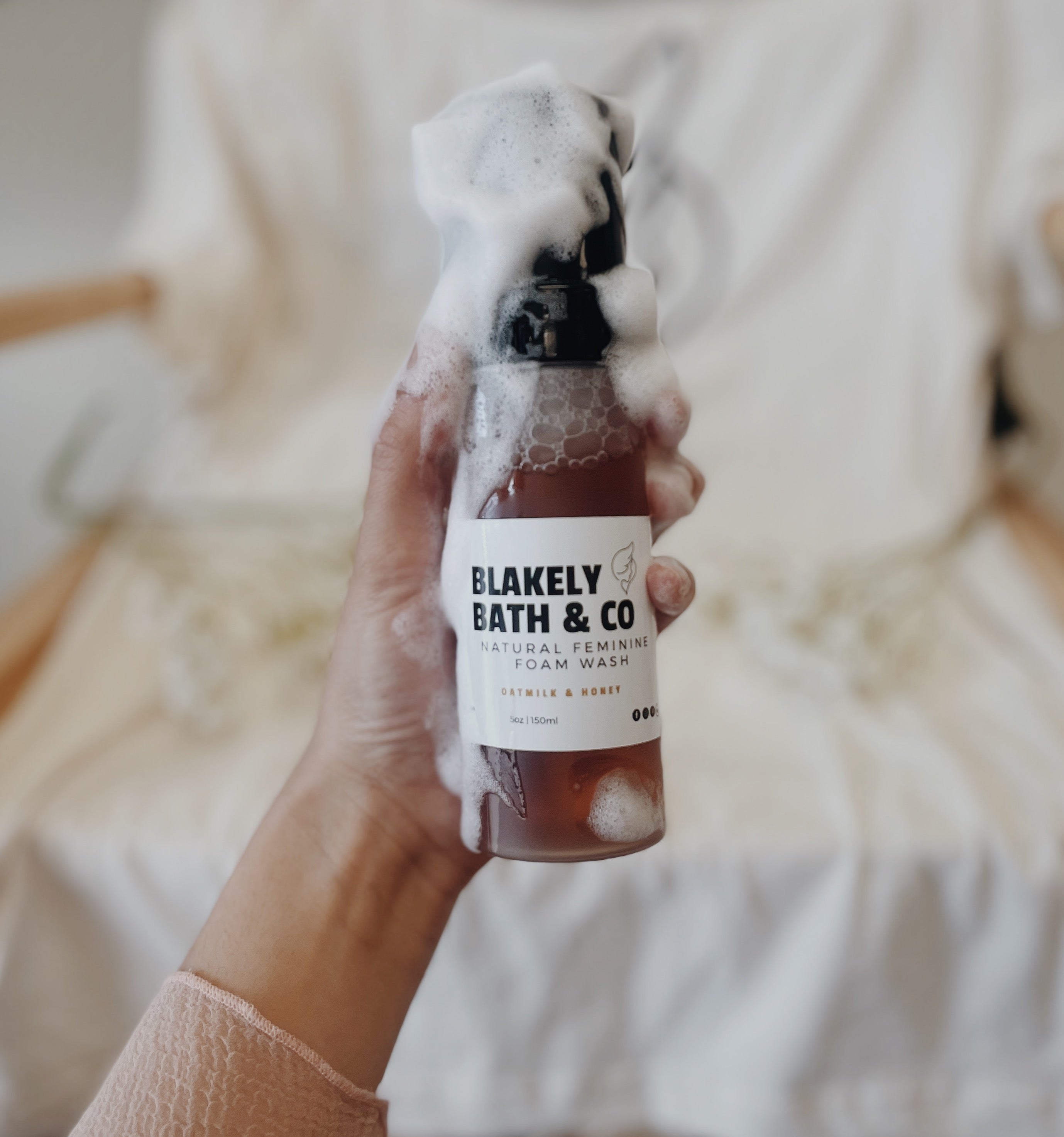 Girl holding bottle of foam wash with soap all over it and her hand