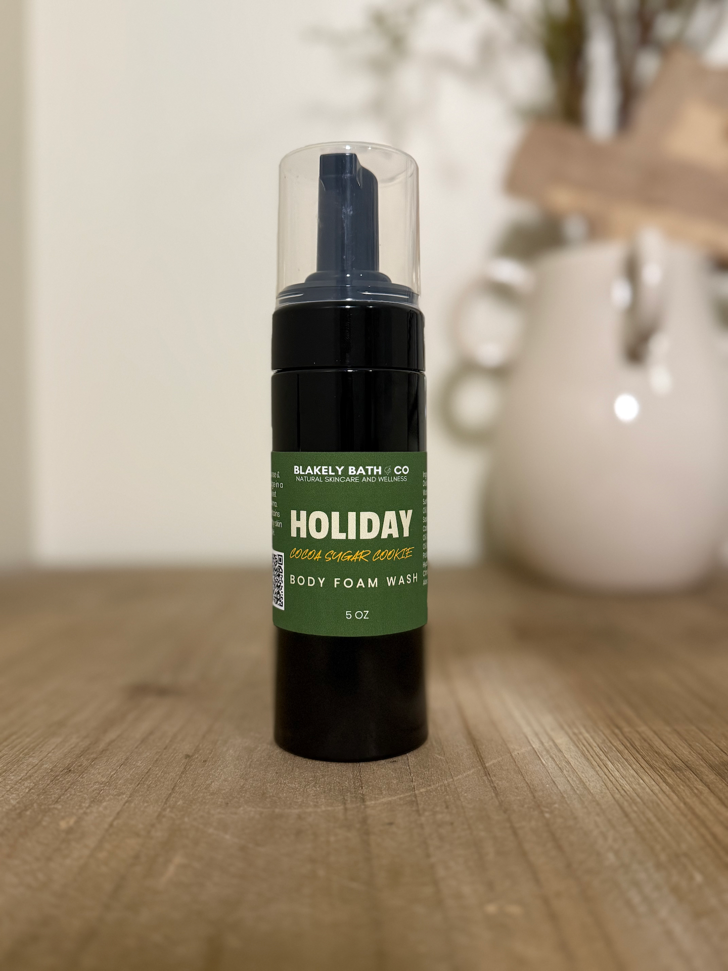 Body wash bottle labeled 'Holiday' on a wooden surface with a blurred background