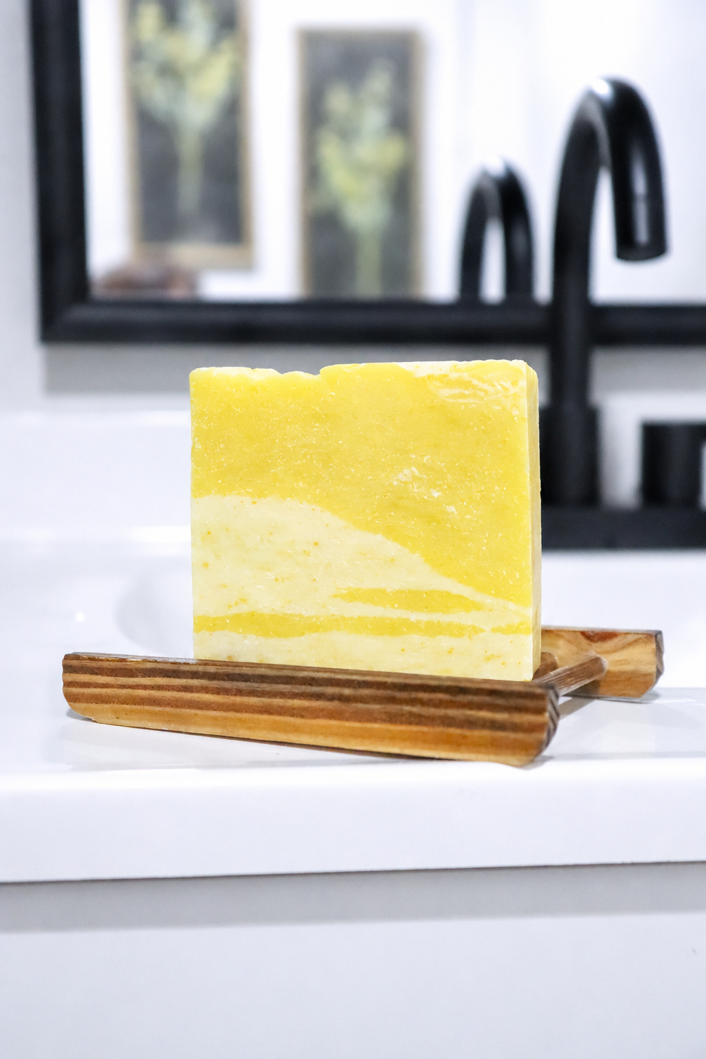 Yellow soap bar on a wooden soap dish with a blurred background
