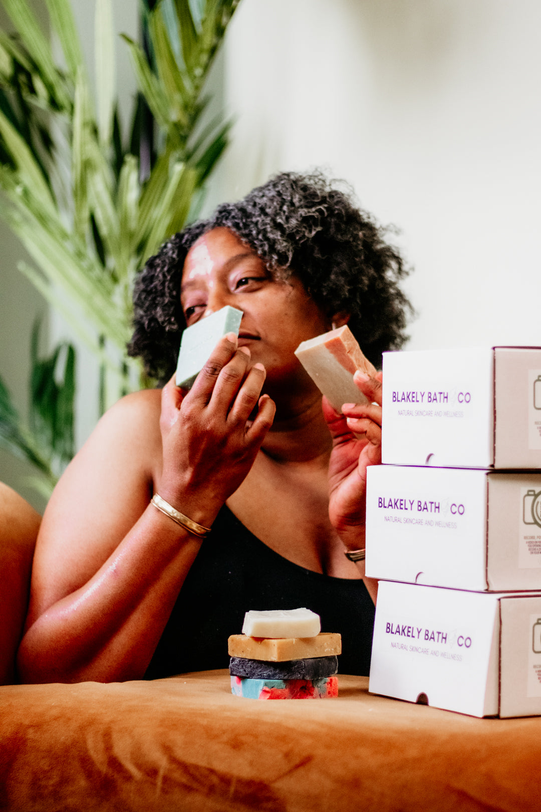 Smiling woman smelling natural bar soap by Blakely Bath & Co, promoting the Soapscription program for Soapscribe members, featuring eco-friendly, skin-nourishing soap bars delivered regularly