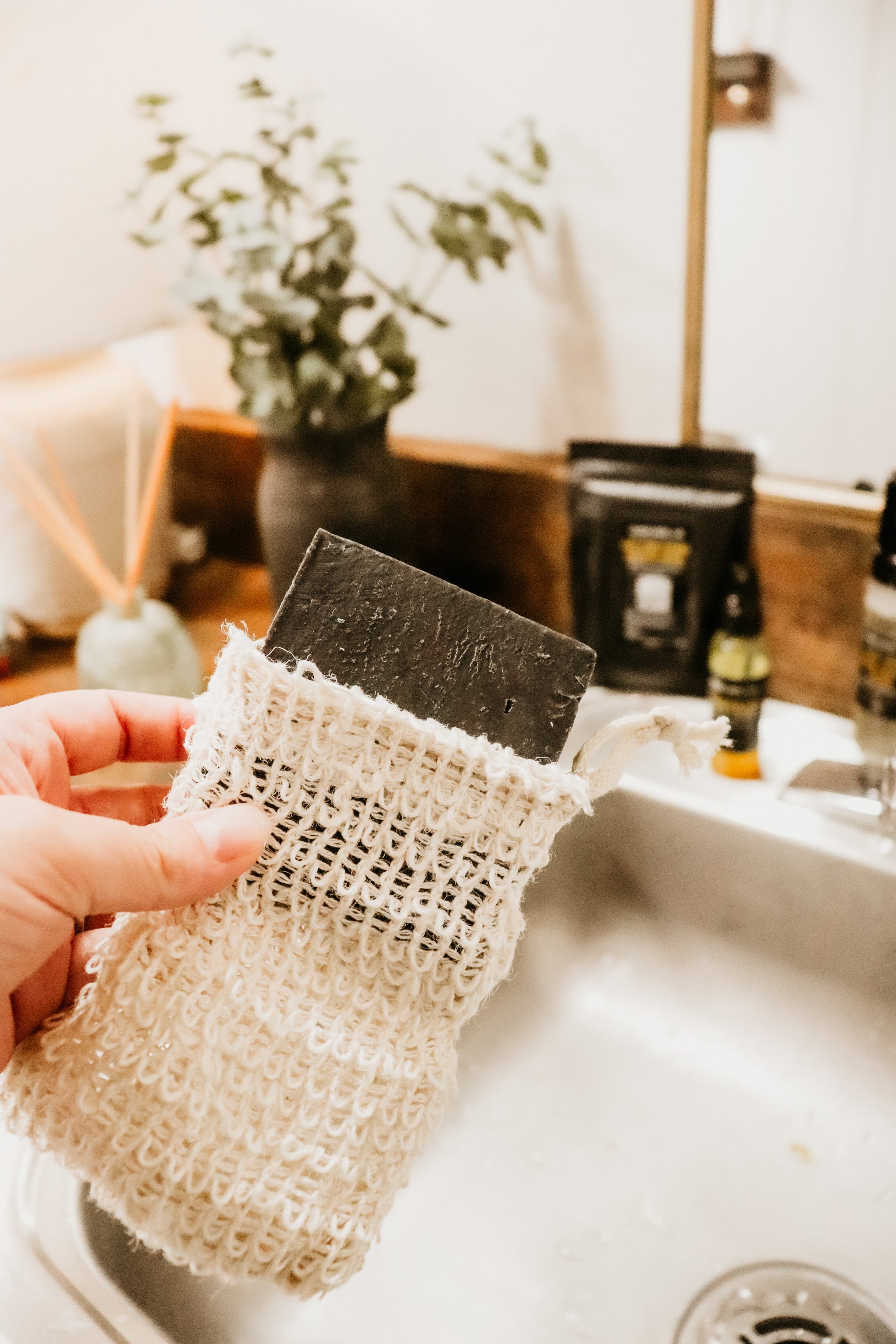 Holding Soap Saver Sack with lavender charcoal soap bar near sink by Blakely Bath & Co