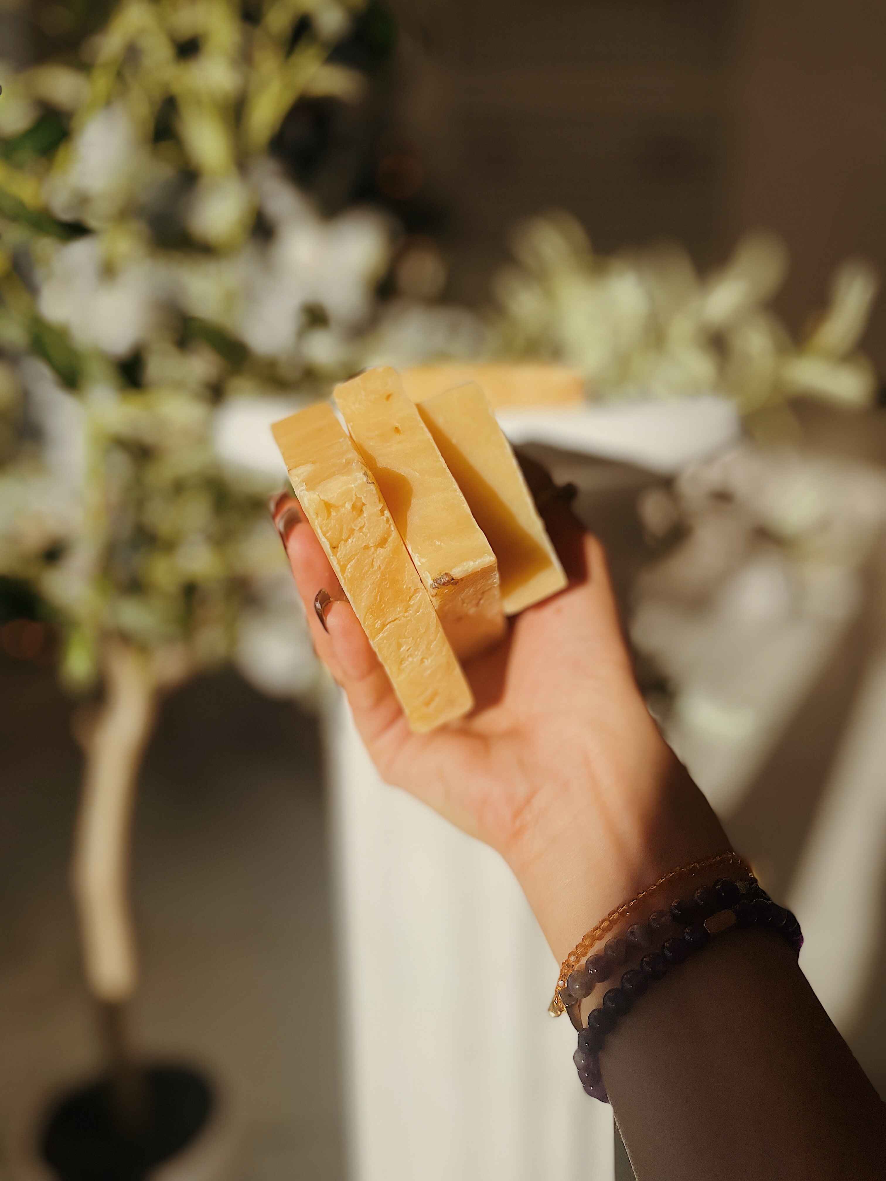 Hand holding three Blakely Bath & Co ThatGlo Turmeric Soap Bars, showcasing the natural soap bars packed with turmeric for glowing, even skin tone and fighting dark spots