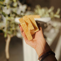 Hands holding ThatGlo Turmeric Soap Bar by Blakely Bath & Co, a natural soap infused with turmeric to brighten skin, reduce dark spots, and promote a glowing complexion