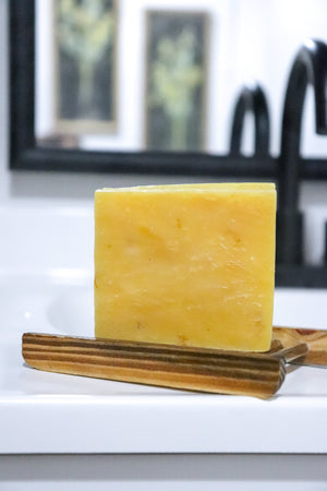 Thatglo Turmeric + calendula  bar of soap on a wooden soap dish by Blakely Bath & Co 