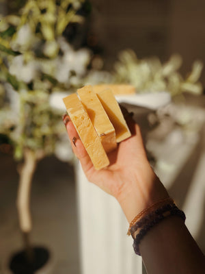 Hands holding ThatGlo Turmeric Soap Bar by Blakely Bath & Co, a natural soap infused with turmeric to brighten skin, reduce dark spots, and promote a glowing complexion