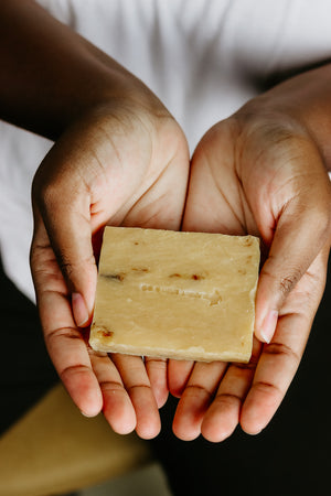 Hands holding ThatGlo Turmeric Soap Bar by Blakely Bath & Co, a natural soap infused with turmeric to brighten skin, reduce dark spots, and promote a glowing complexion