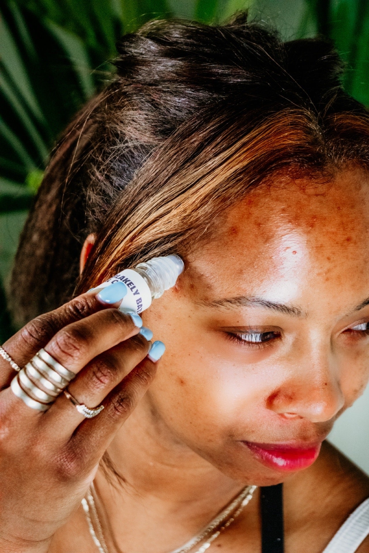 Sade Campblel, owner of Blakely Bath & Co, applying the Natural Migraine Relief Roller to her head, enjoying the soothing effects of the essential oils for headache relief and relaxation