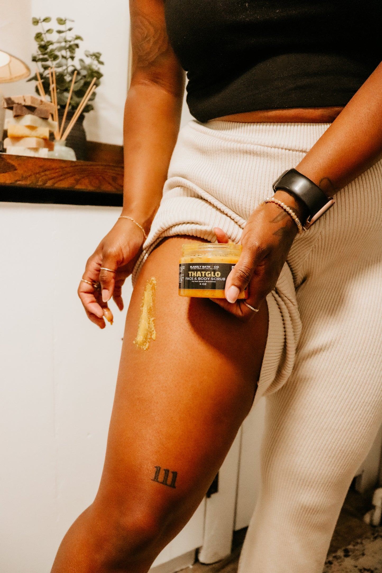 Woman applying Turmeric Brightening Scrub to their leg with a focus on the application process.