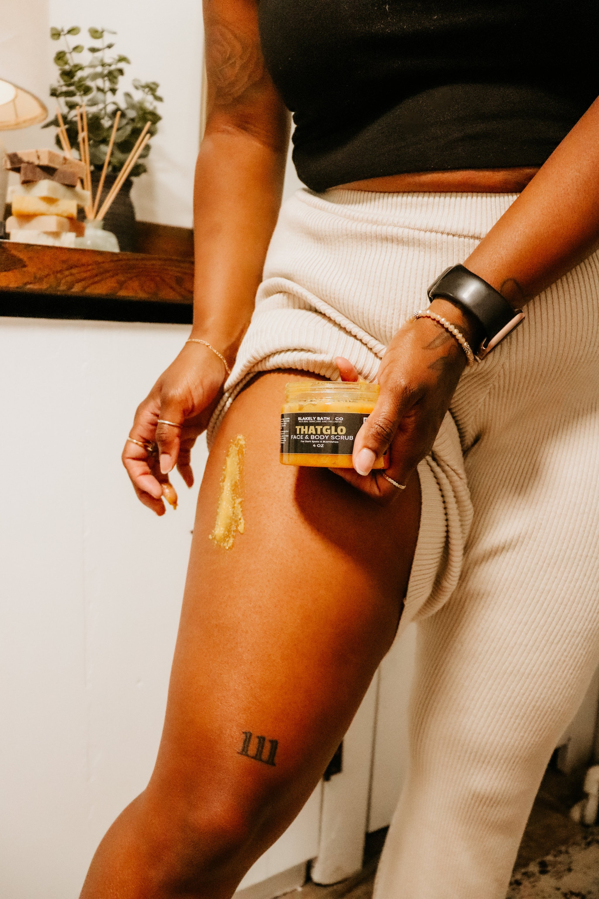 Woman applying Turmeric Brightening Scrub to their leg with a focus on the application process.