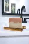 Cherry Almond soap bar by Blakely Bath and Co of soap on a wooden soap dish with a blurred bathroom background