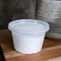 Family size clear PET plastic container of Silk Dream Cream by Blakely Bath and Co on a wooden surface