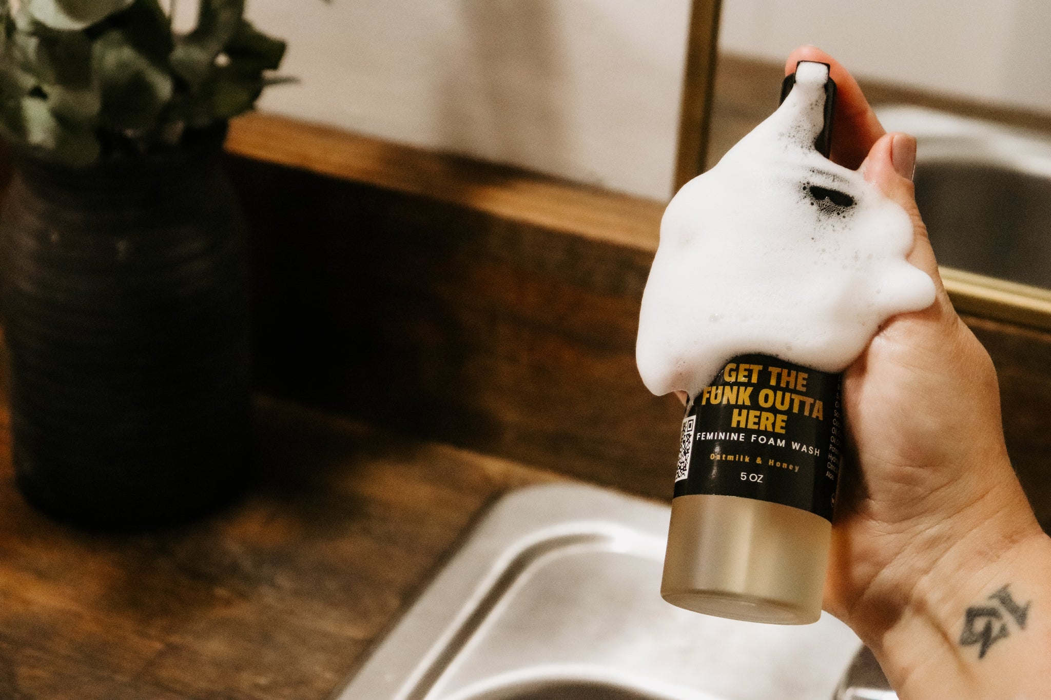 Girl holding Blakely Bath & Co Feminine Foam Wash bottle with soap lathered on her hand and the bottle, demonstrating the rich foam and gentle cleansing formula