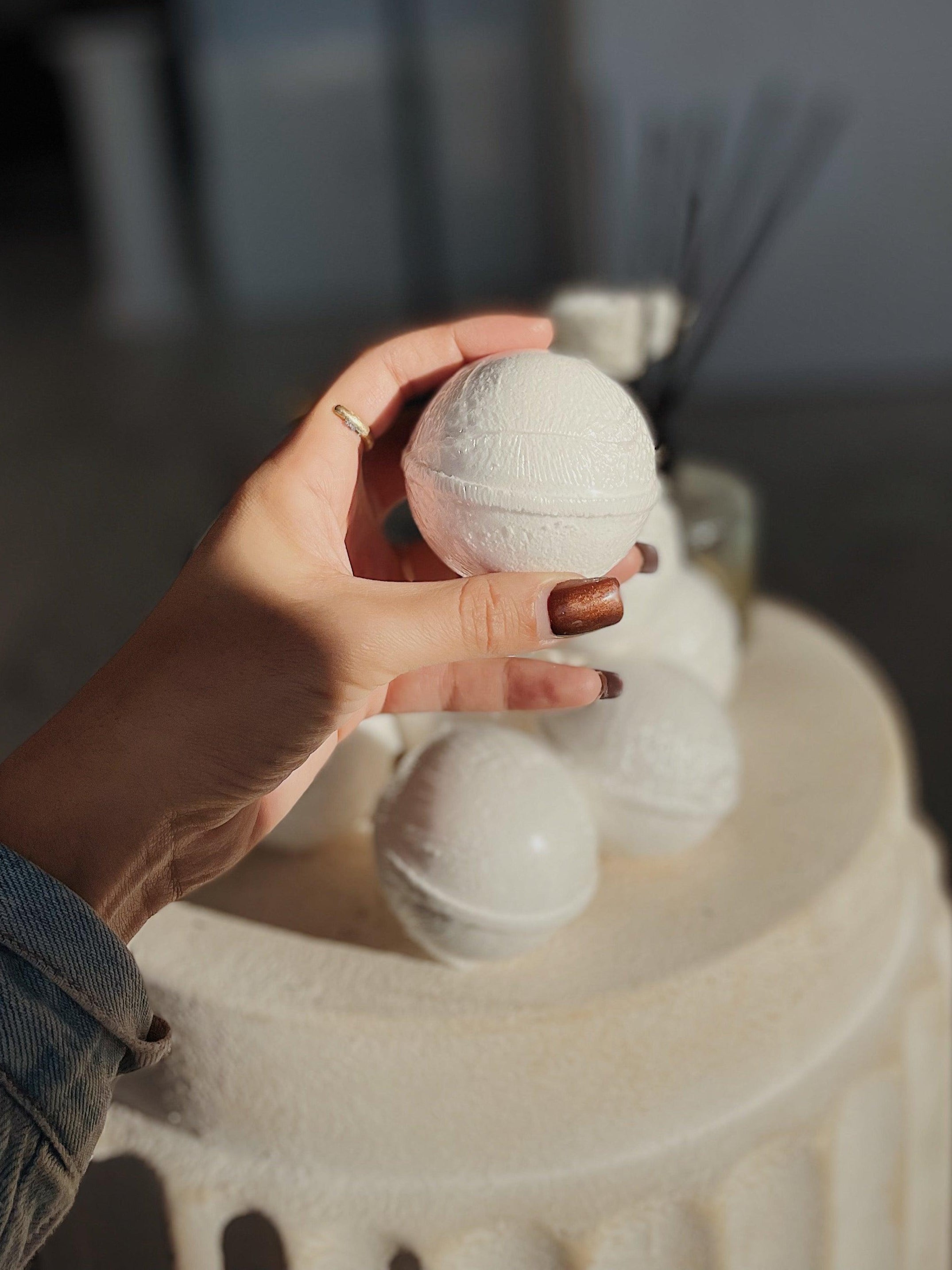 Holding Blakely Bath & Co Detox Bath Bomb, showcasing its vibrant color and natural ingredients, ready to dissolve in the bath for a soothing, cleansing experience