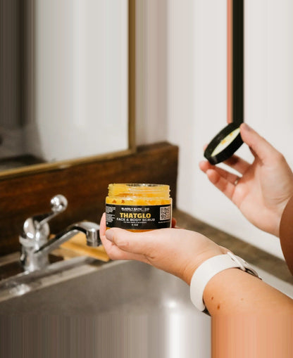 Person holding a jar of ThatGro hair product in front of a bathroom sink.
