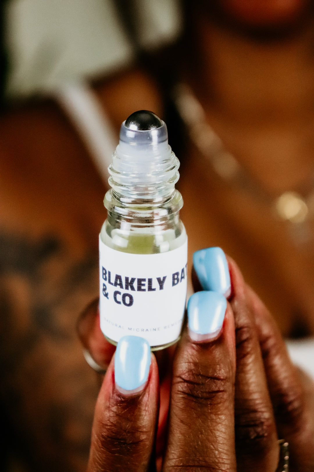 Sade Campbell, owner of Blakely Bath & Co, holding the Migraine Relief Roller, ready to apply the natural blend of essential oils to ease headaches, tension, and migraines