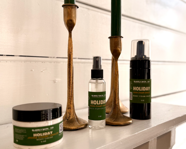 Bath and body products with 'Holiday' label on a shelf with candles.