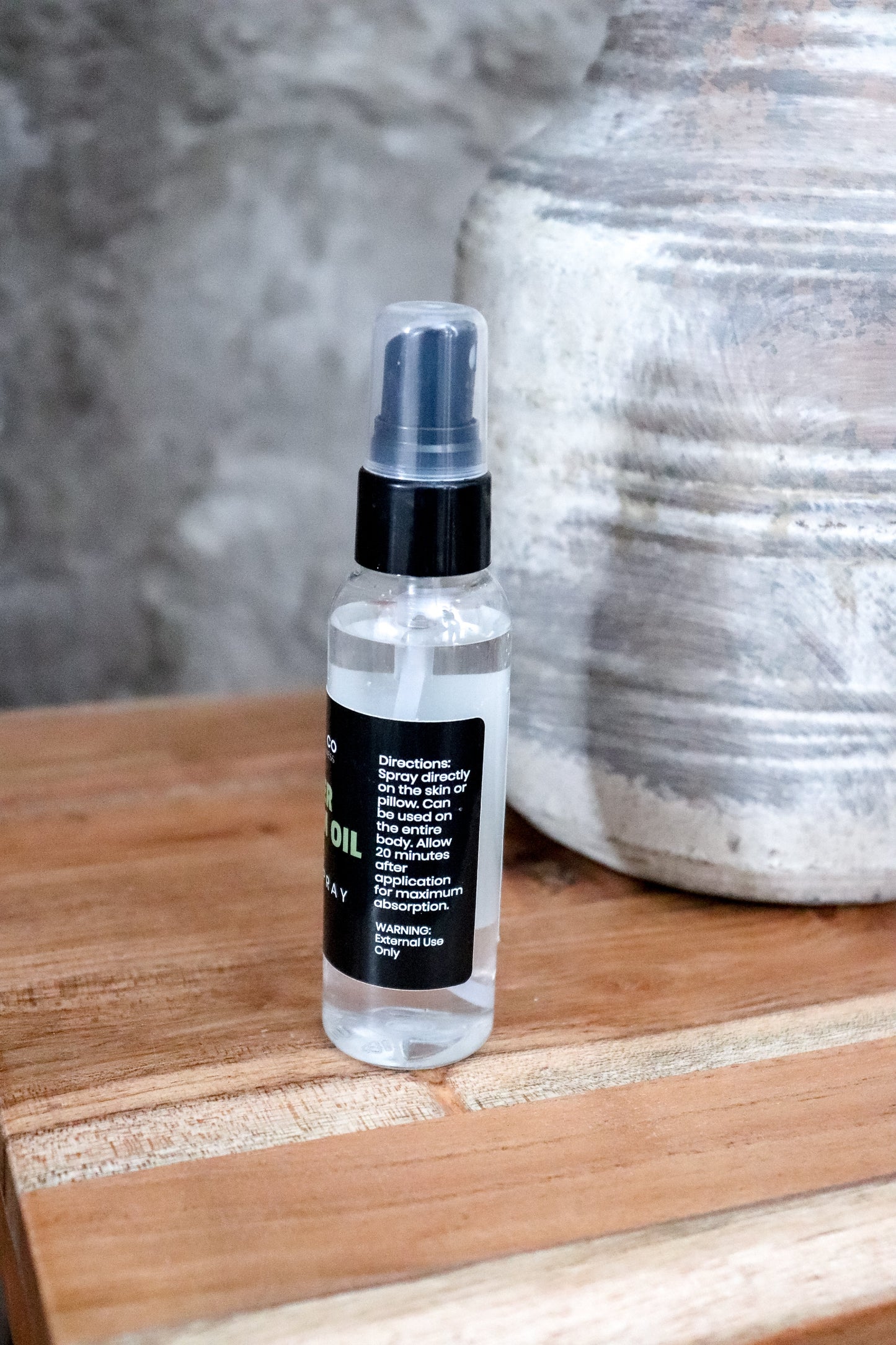 Lavender Magnesium oil spray bottle with directions on label sitting on a wooden surface with a textured background