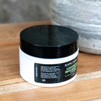 Jar of Lavender Magnesium Cream with black lid on a wooden surface showing directions on use