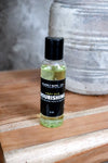 Bottle of Nourishing Face and body oil  on a wooden surface with a blurred background by Blakely Bath & Co 