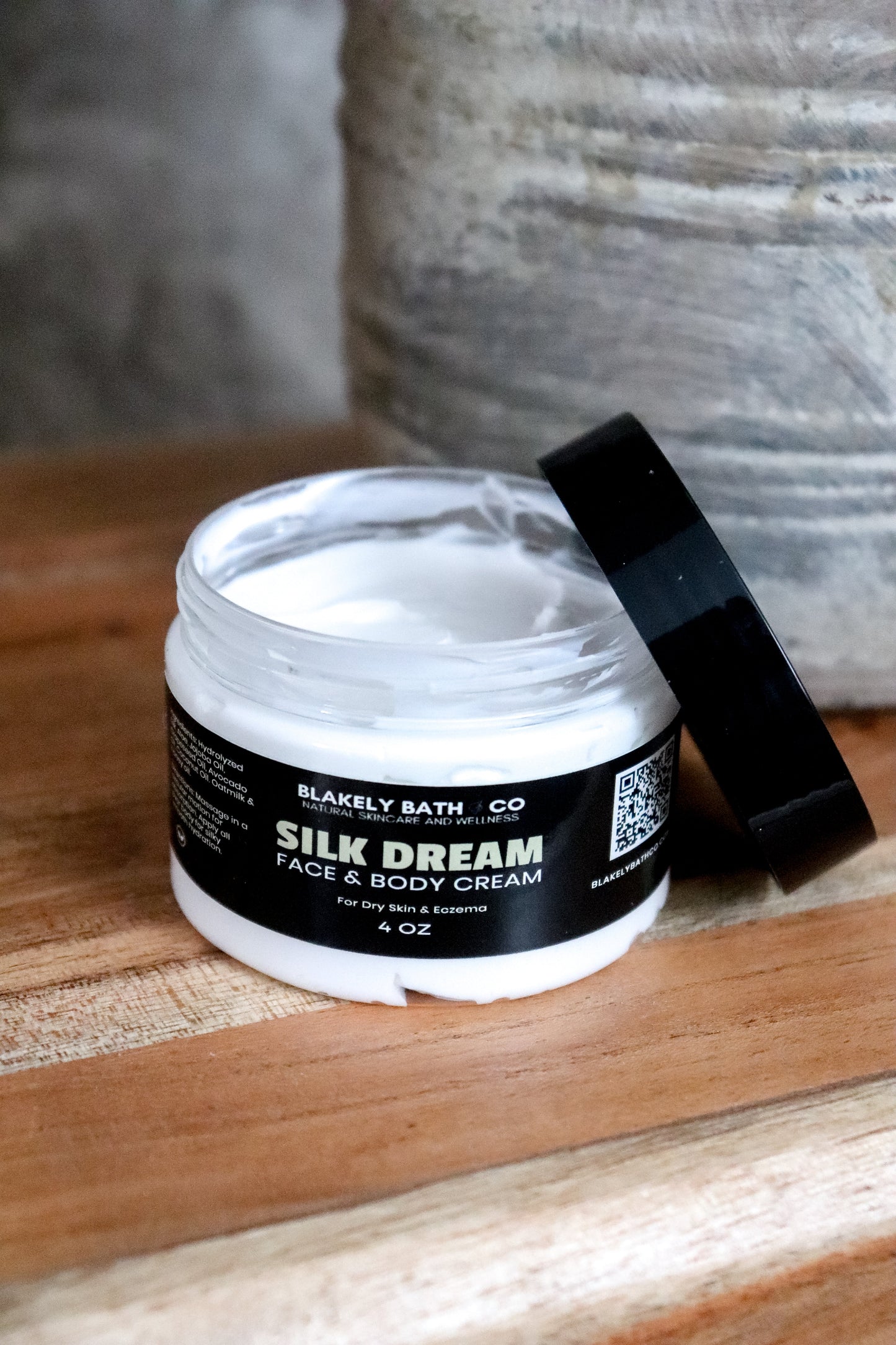 Jar of Silk Dream face and body cream on a wooden surface with a neutral background