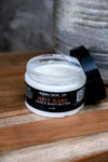 Jar of Blakely Bath Co. Hot Girl Face & Body Butter on a wooden surface with a blurred background