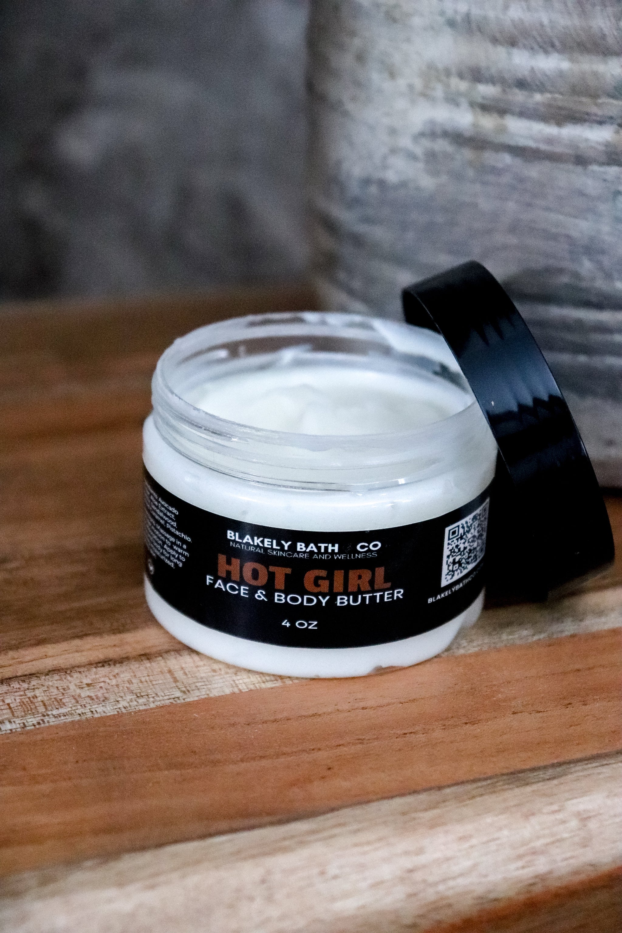 Jar of Blakely Bath Co. Hot Girl Face & Body Butter on a wooden surface with a blurred background