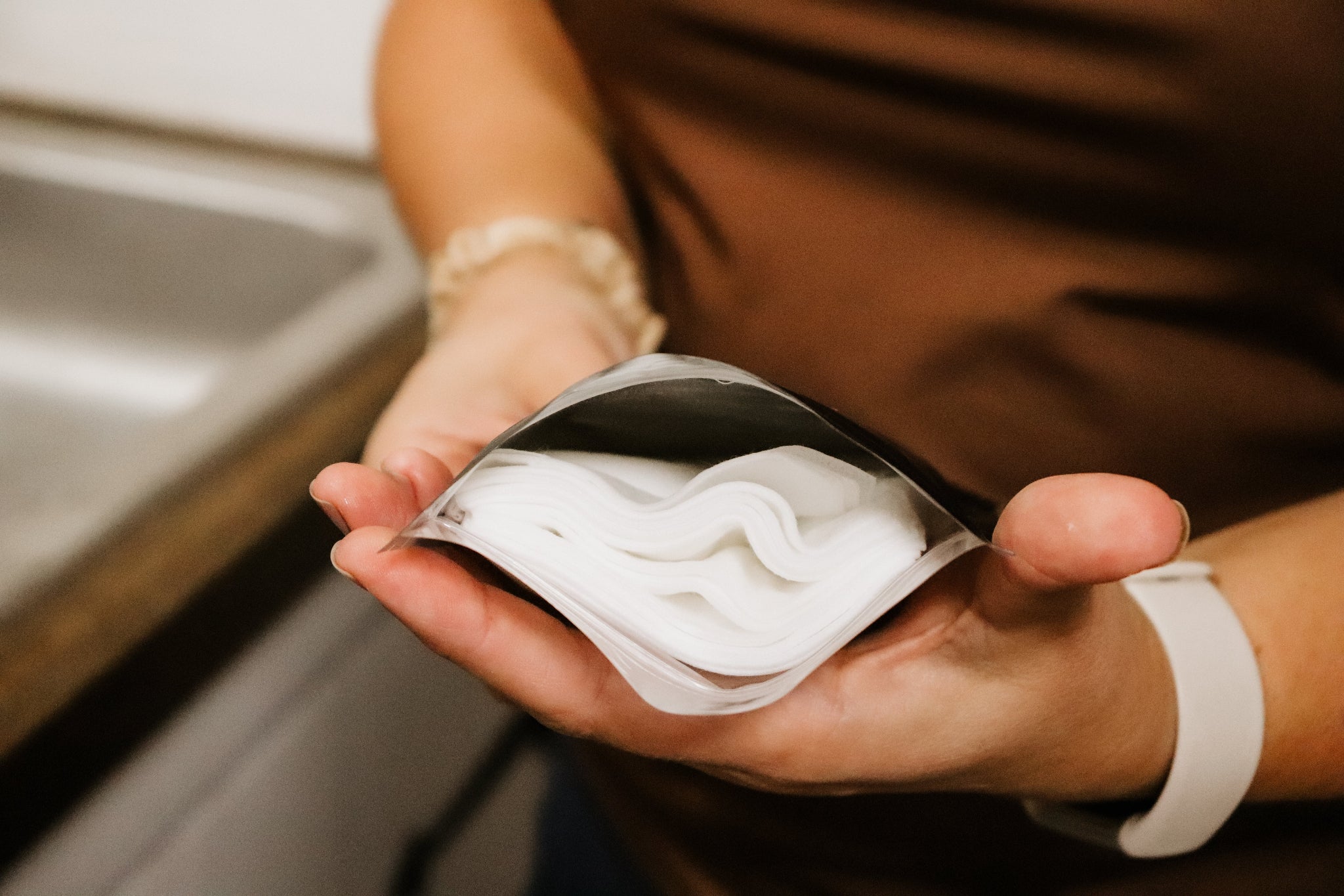 woman holding a package of Feminine Wipes by bathroom sink