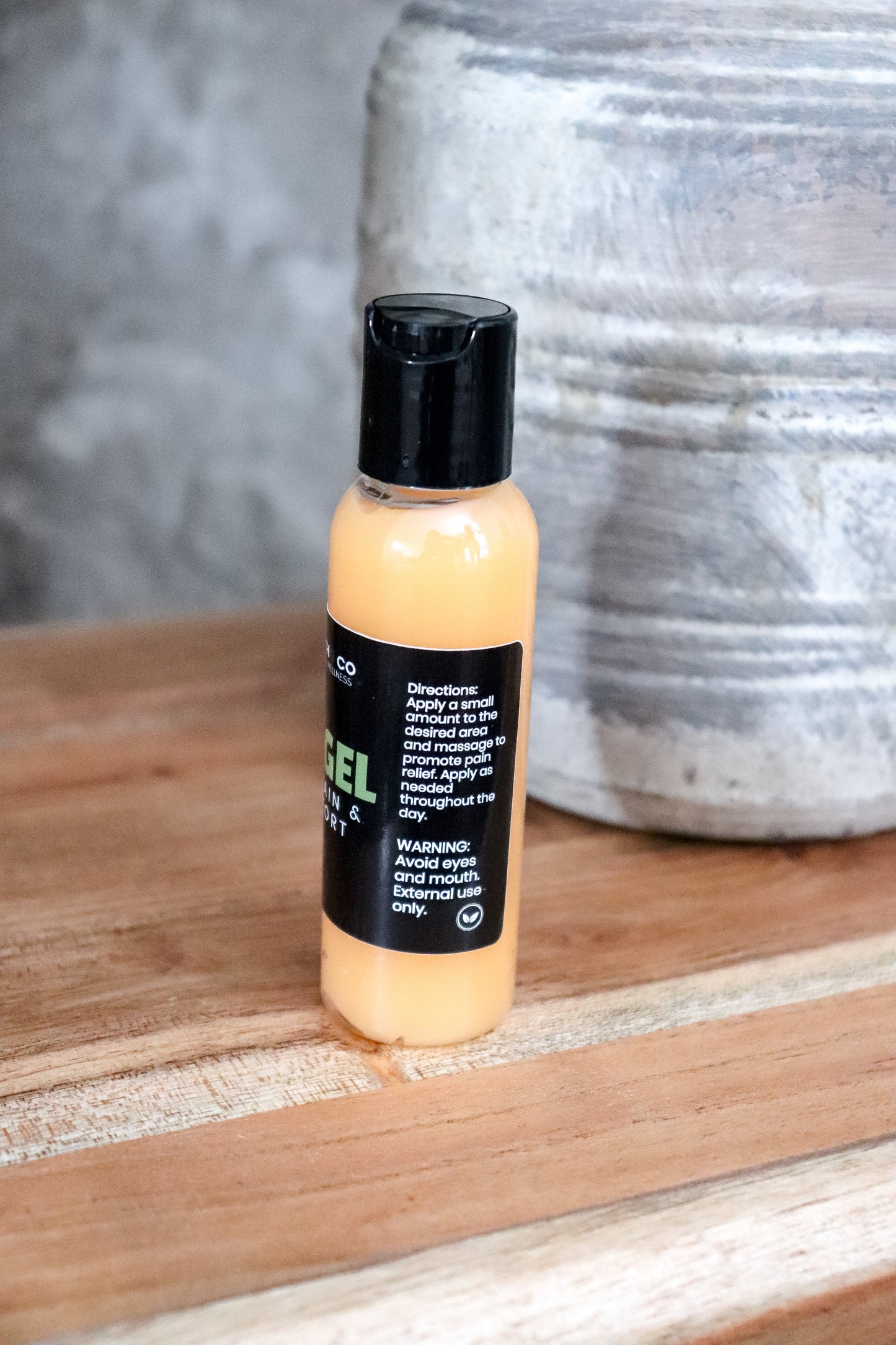 Bottle of pain gel on a wooden surface with a textured wall in the background