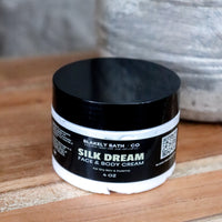 Jar of Blakely Bath Co Silk Dream Face & Body Cream on a wooden surface with a textured gray background best natural skincare moisturizer for radiant, hydrated, and silky smooth skin.