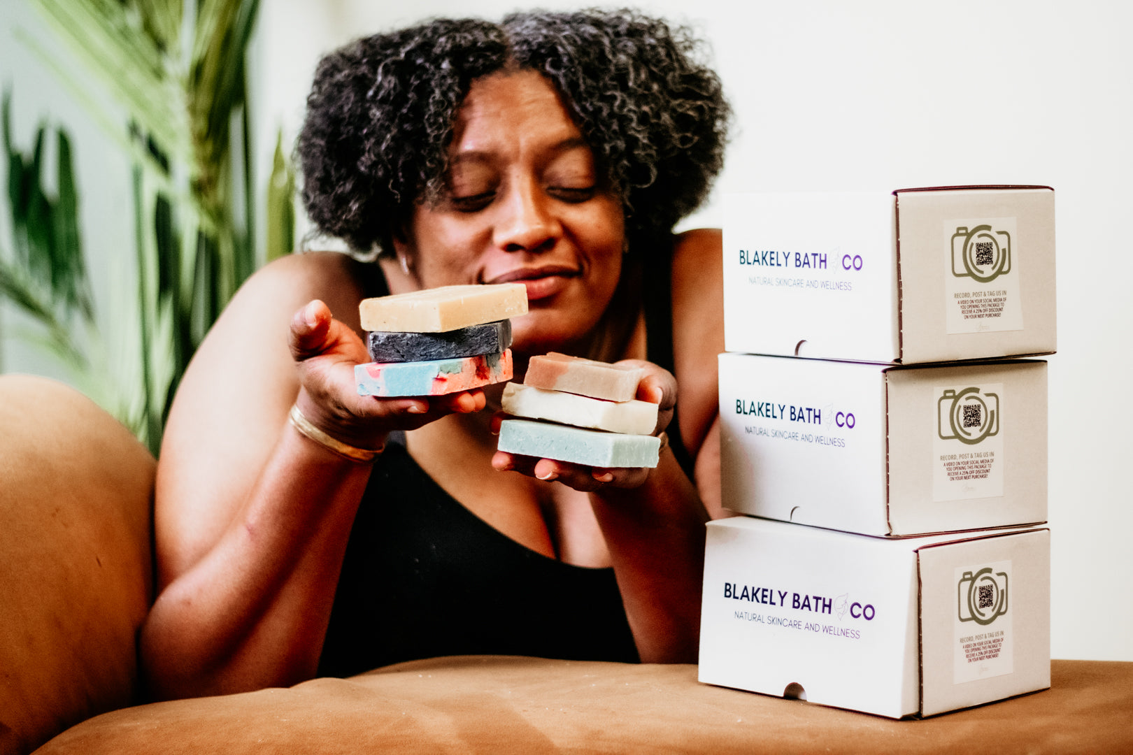 Smiling woman holding a natural bar soap by Blakely Bath & Co, promoting the Soapscription program for Soapscribe members, featuring eco-friendly, skin-nourishing soap bars delivered regularly