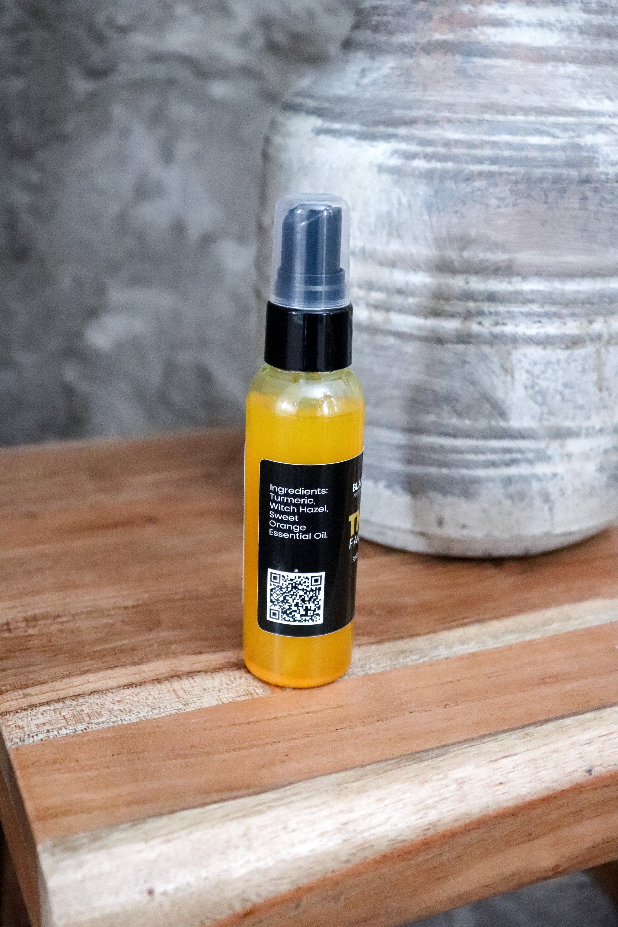 Bottle of yellow liquid with a black label on a wooden surface