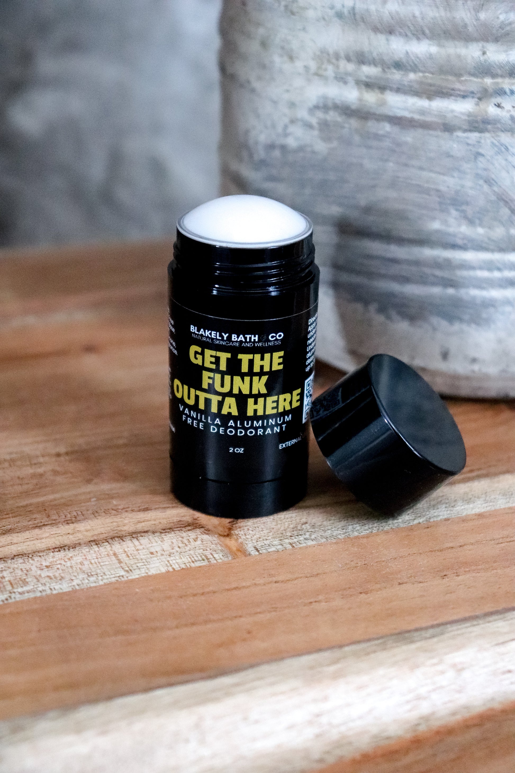 vanilla aluminum deodorant stick with top off  on a wooden surface
