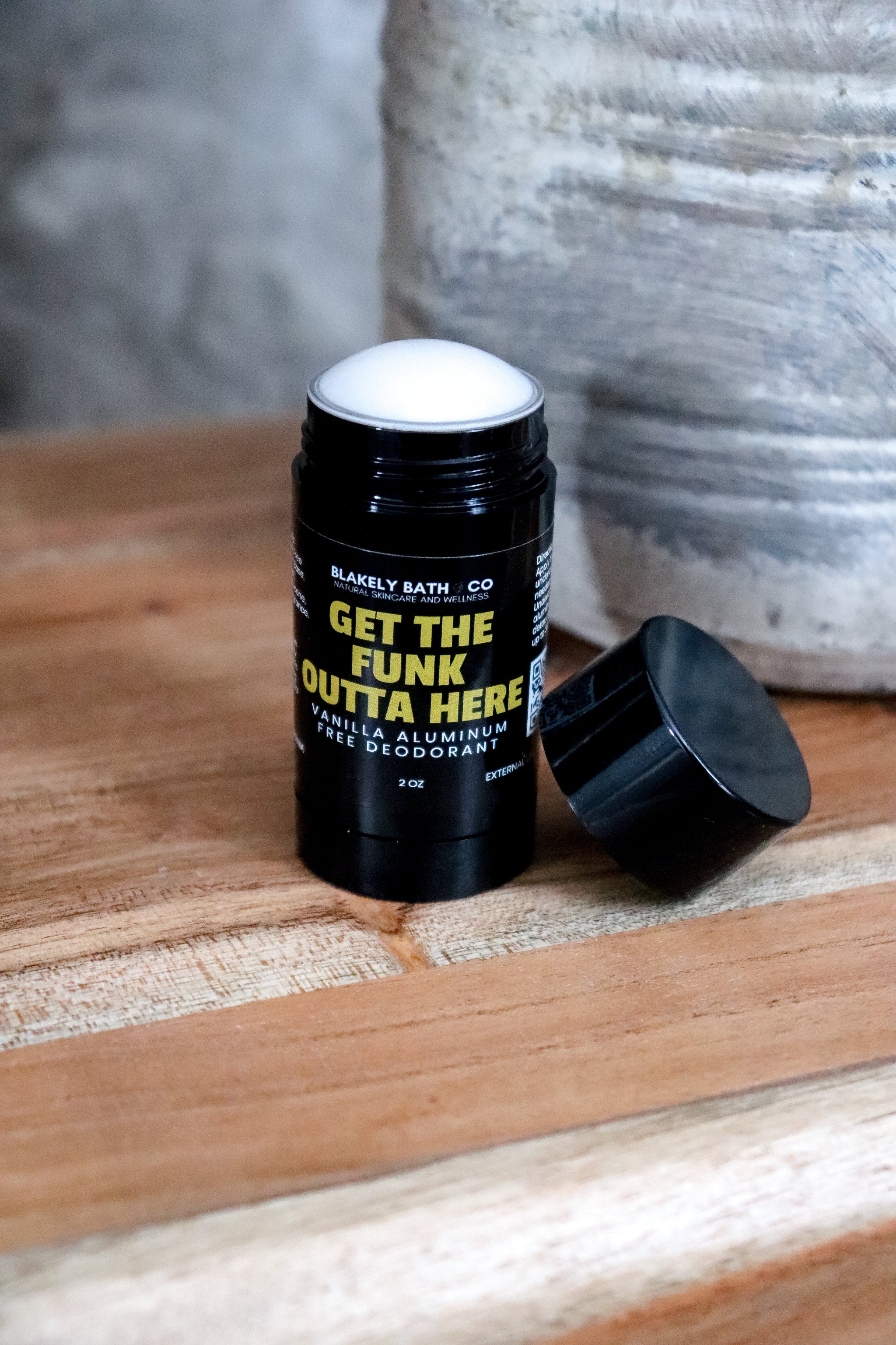 vanilla aluminum deodorant stick with top off  on a wooden surface