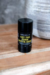Vanilla aluminum deodorant stick with black and yellow label on a wooden surface