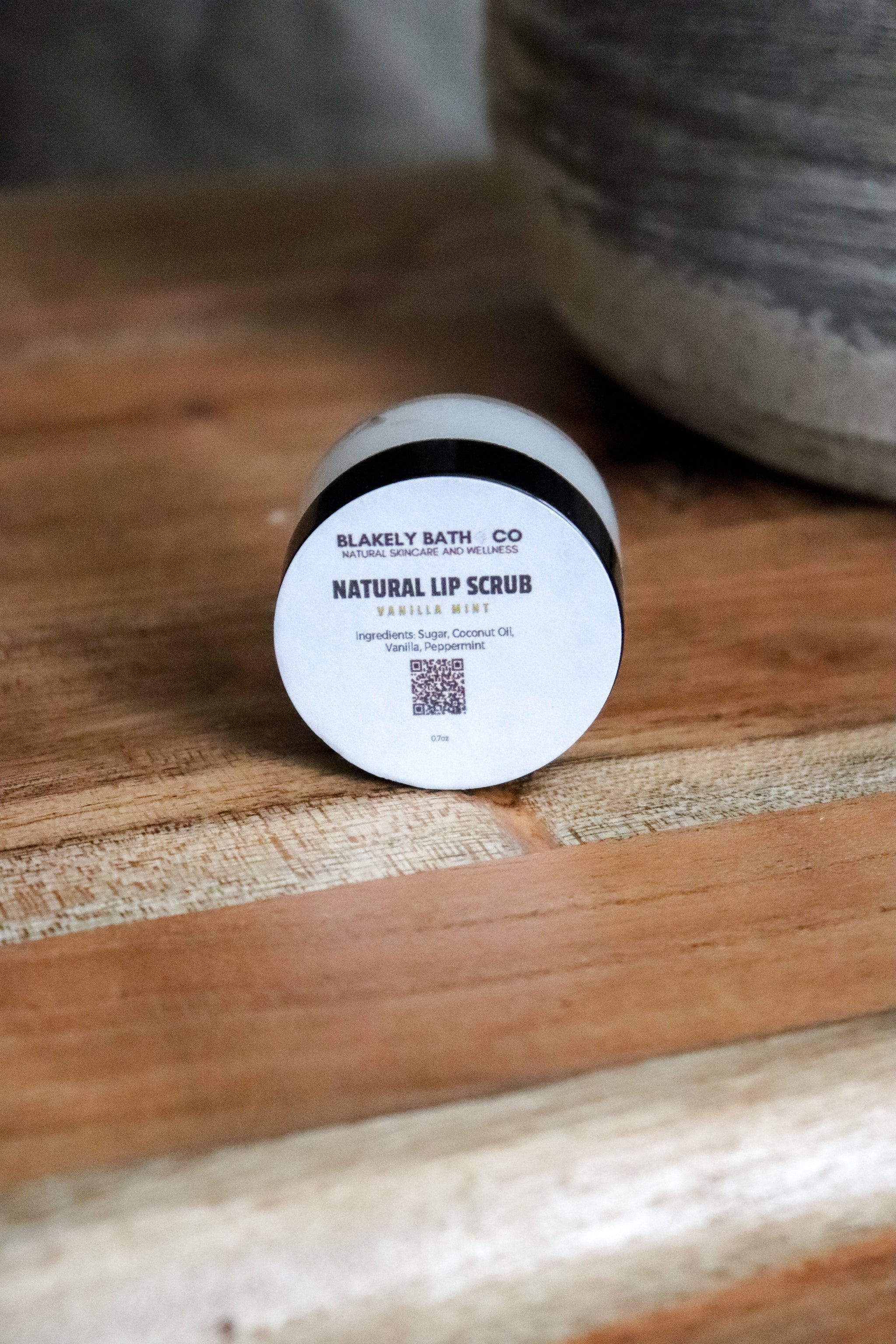 Round container of Blakely Bath Co natural vanilla mint liip scrub on a wooden surface