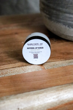 Round container of Blakely Bath Co natural vanilla mint liip scrub on a wooden surface